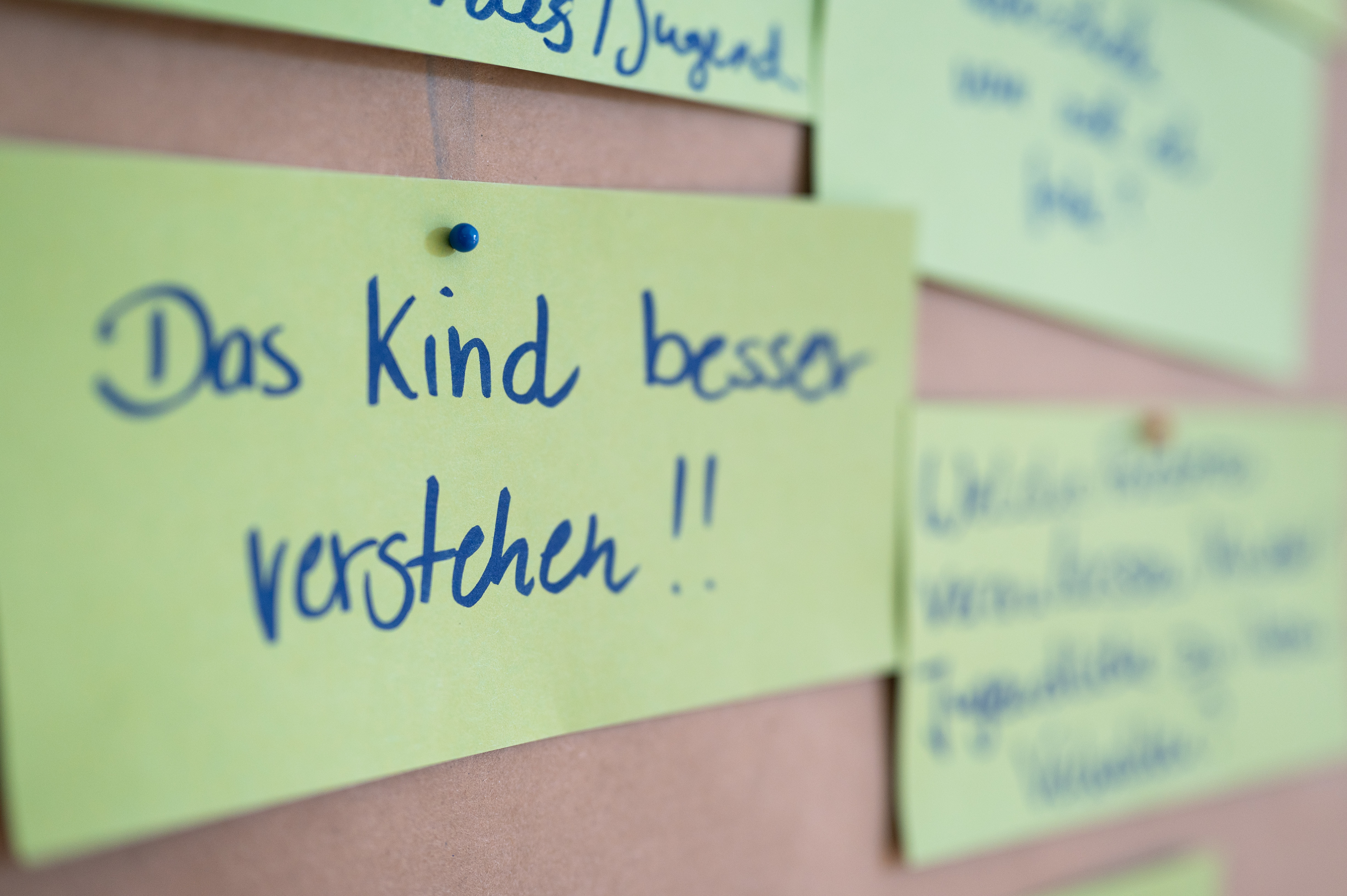 Ein Zettel, der an einer Pinnwand steckt. Dort steht: Das Kind besser verstehen!