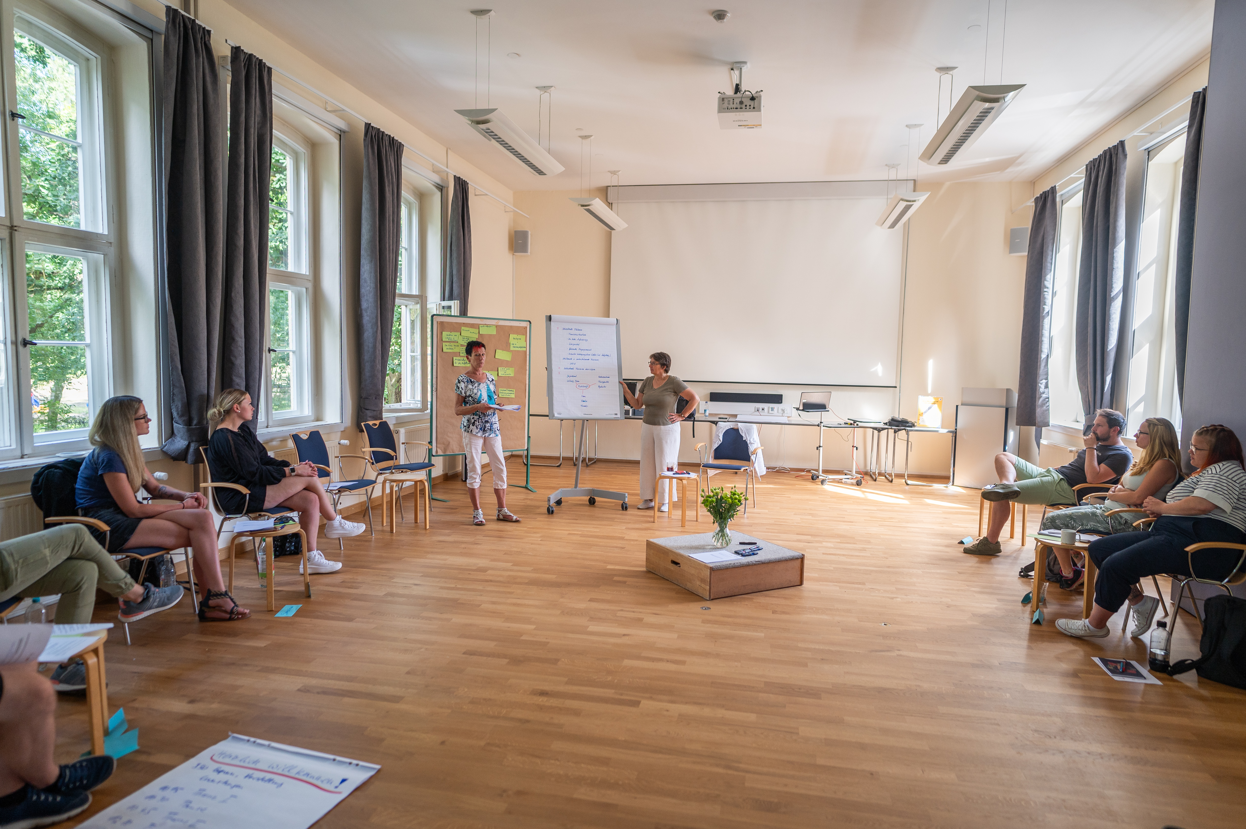 Ein Saal mit Menschen, die im Kreis sitzen.